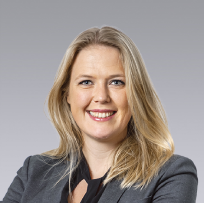 a headshot of a blonde woman in a blue suite jacket smiling at the camera