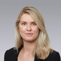 a headshot of a blonde woman in a blue suite jacket smiling at the camera