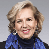 a headshot of a blonde woman in a blue suite jacket smiling at the camera