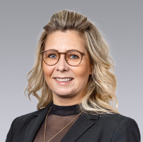 a headshot of a blonde woman in a blue suite jacket smiling at the camera