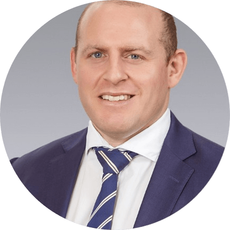 a headshot of a blonde woman in a blue suite jacket smiling at the camera