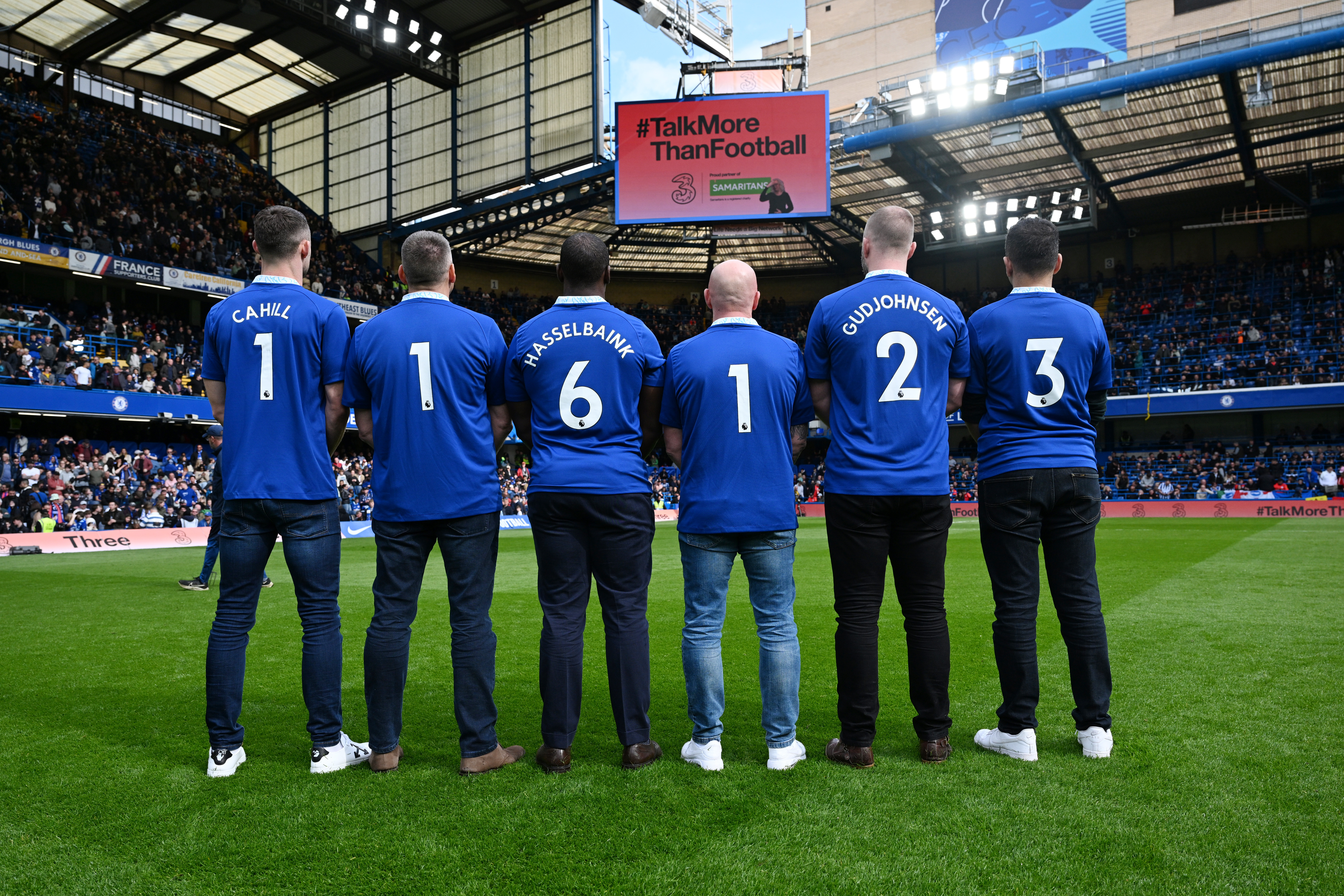 Chelsea FC legends Jimmy Floyd Hasselbaink, Eiður Guðjohnsen, and Gary Cahill stand on Football Field