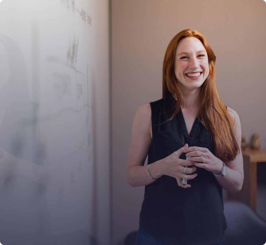 An image of a woman standing at a white board