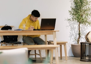 An image of a man looking at a computer while sitting at a desk 