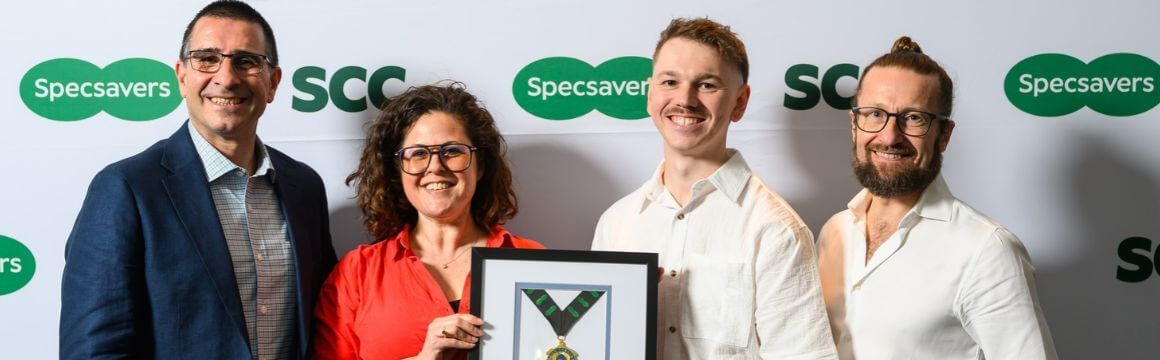 A group of four people smile with an award plaque