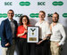 A group of four people smile with an award plaque