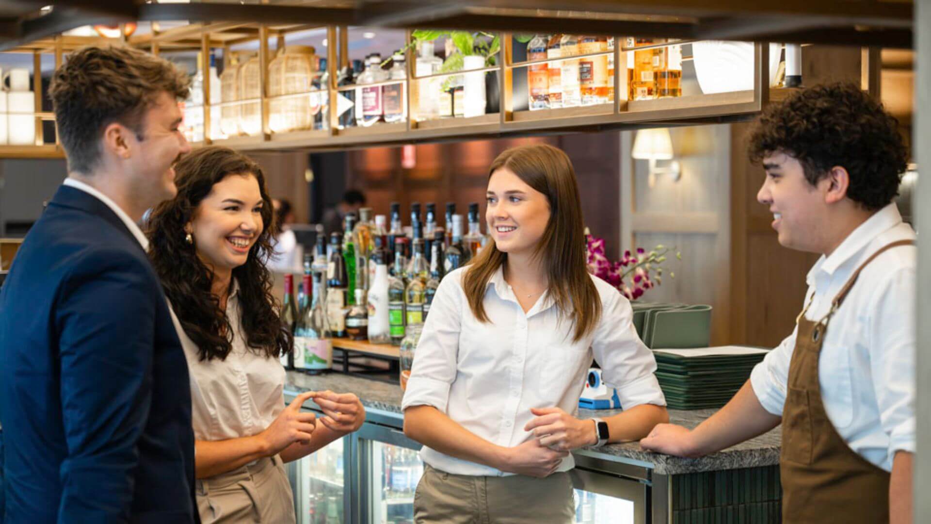 Four front of house Heartists having a fun conversation by the bar in the hotel.