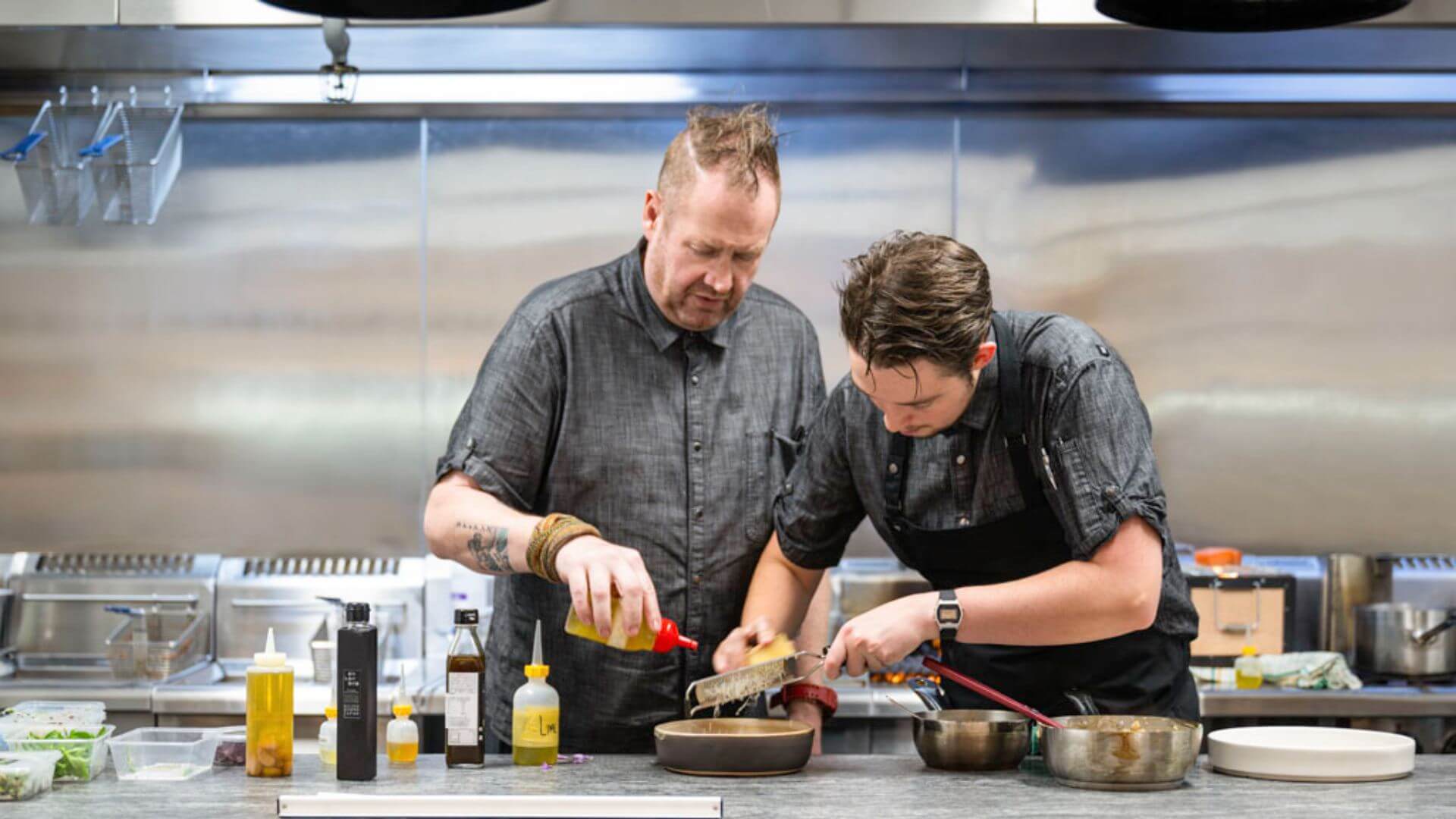 Two chefs preparing a dish in the kitchen.