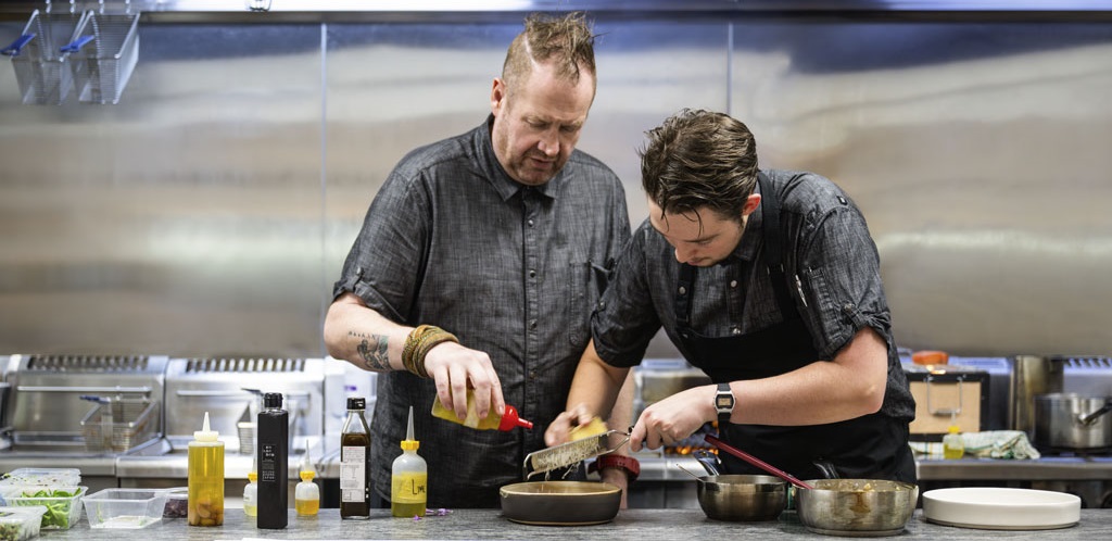 Two chefs preparing a dish in the kitchen.