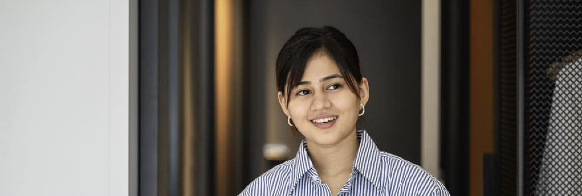 housekeeper with blue shirt holding towels and smiling 