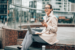 image of design professional sitting on steps with laptop and phone 