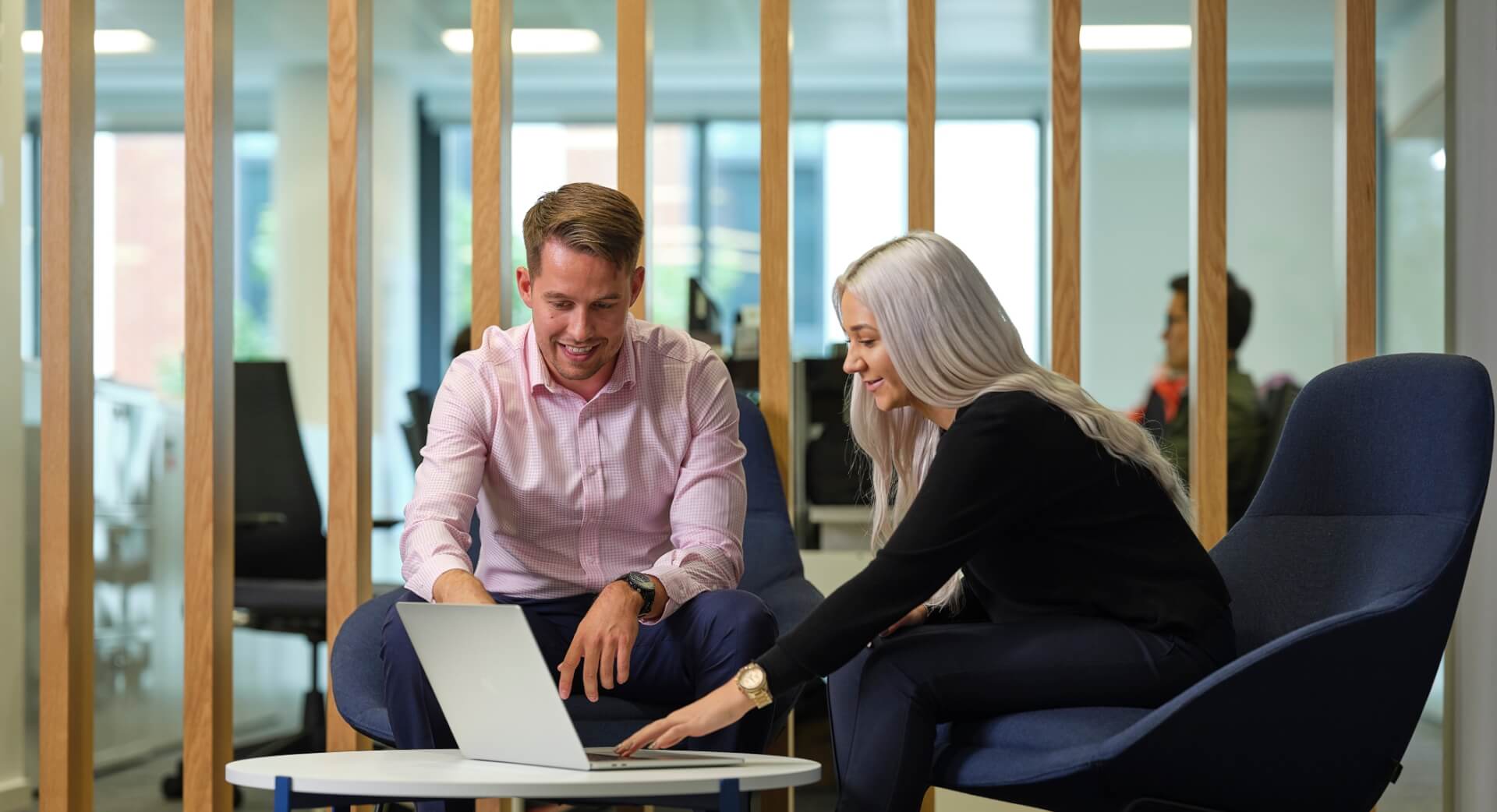 A man and a woman working on a laptop in an office