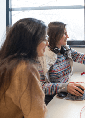 women sitting on a bed using a laptop