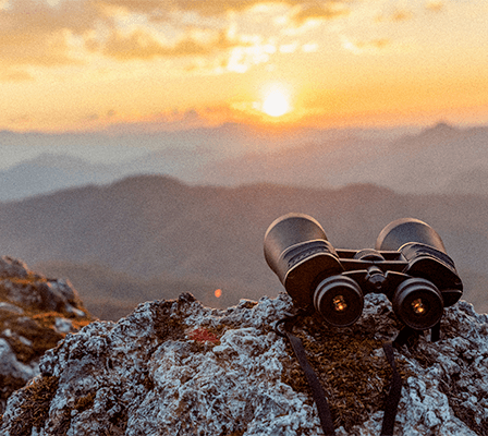 Binoculars on a mountain in front of a sunset