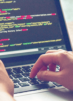 a hand typing on a computer keyboard, displaying lines of code.