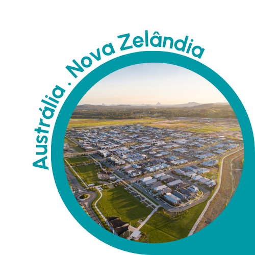 Uma imagem circular com uma borda azul-petróleo mostrando uma vista panorâmica de uma área suburbana na Austrália ou Nova Zelândia. A imagem apresenta um bairro residencial bem organizado com fileiras de casas, gramados verdes e ruas sinuosas. O plano de fundo inclui campos abertos e colinas distantes sob um céu claro. O texto “Austrália . Nova Zelândia” está escrito em azul-petróleo, curvando-se ao longo da borda superior esquerda do círculo, indicando o contexto da Austrália e da Nova Zelândia.