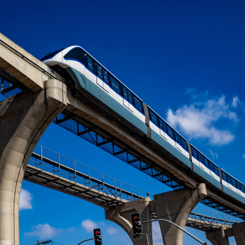 A modern monorail train traveling on elevated tracks against a clear blue sky.