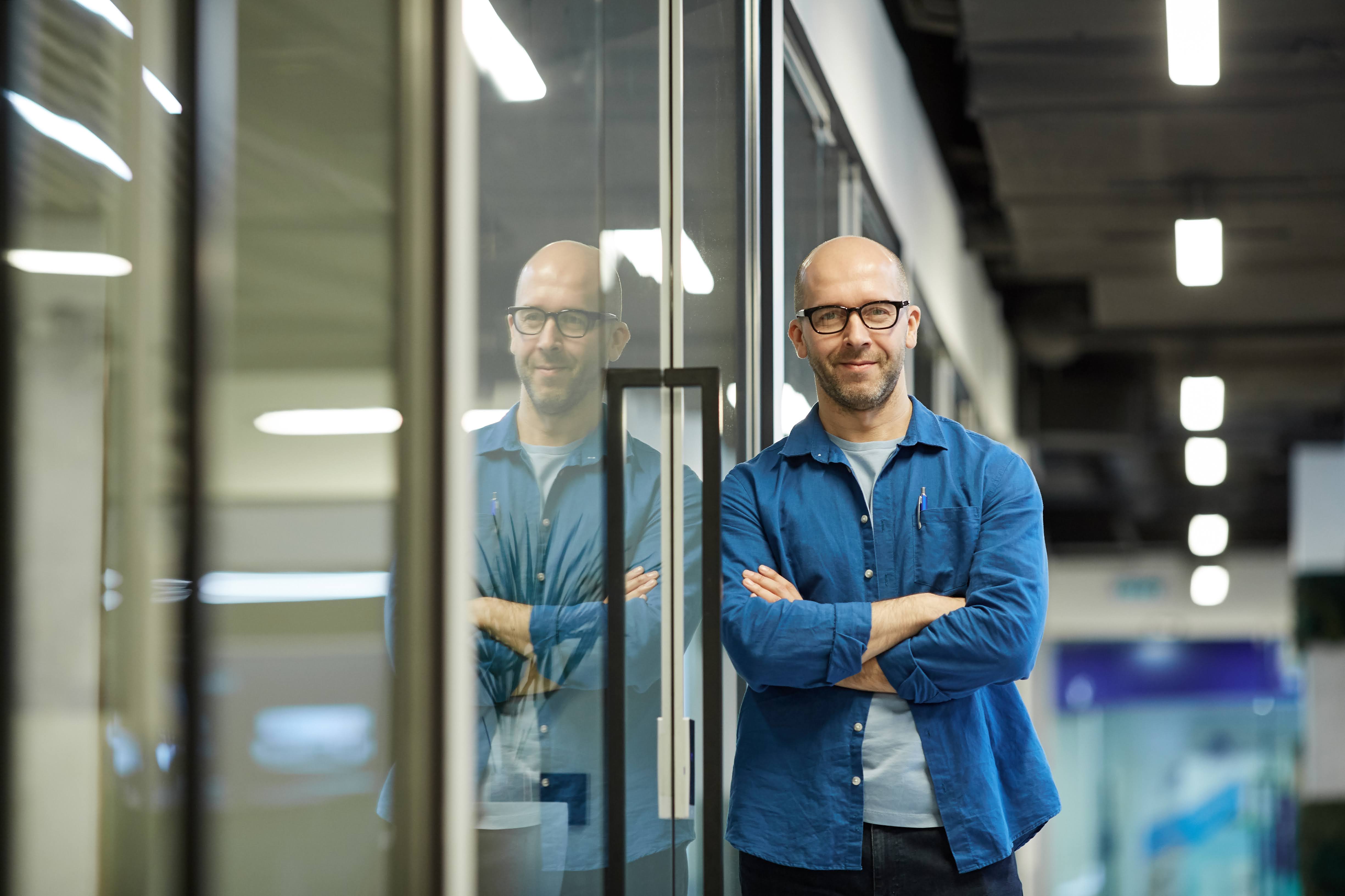 Man leaning against a door where you can see his reflection 