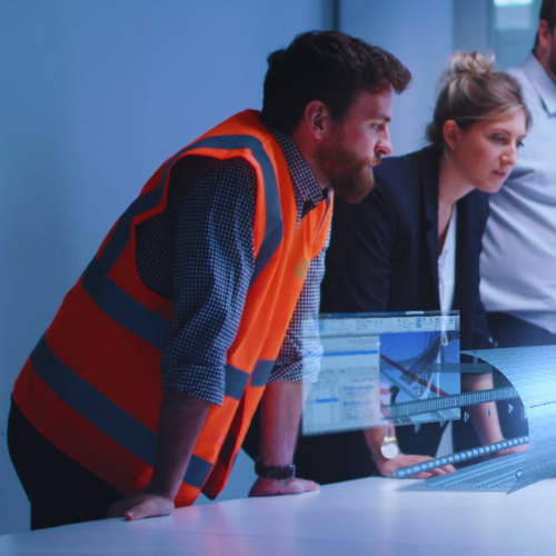 Two people in high vis jackets looking at floor plans on digital tablets