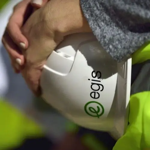 Hands holding a white safety helmet with the "egis" logo on it.