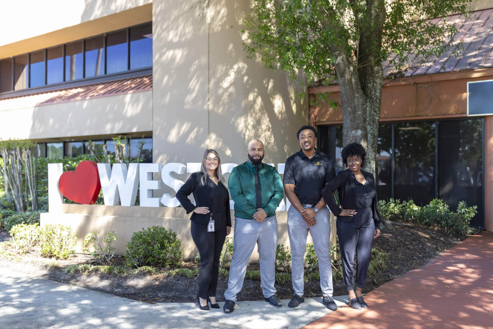 four Westgate employees standing smiling in front of a sign that says I love Westgate