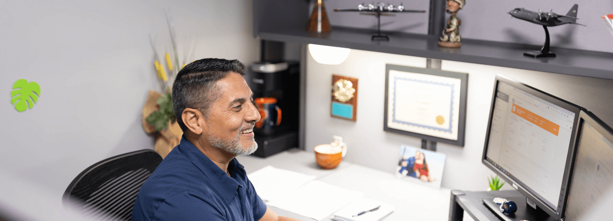 Man smiling at a desk, typing.