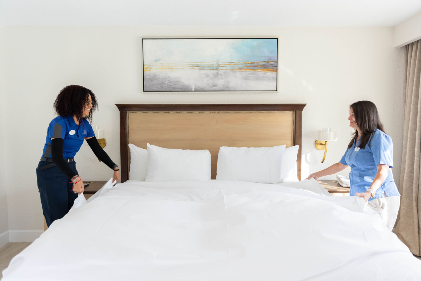 two housekeepers making a hotel bed