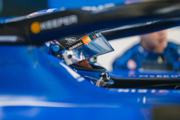 A Williams F1 driver behind the wheel of a car wearing a helmet