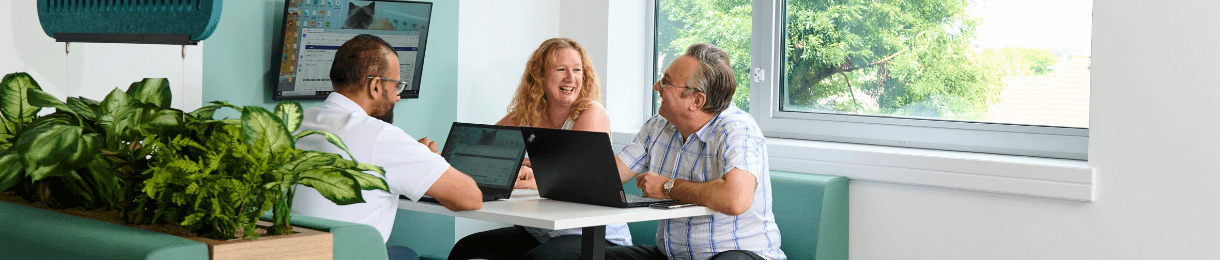 Three Medivet employees sat in a booth, chatting with laptops.