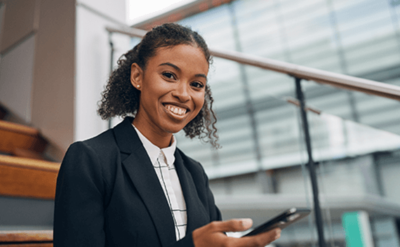 A woman sitting with her phone, smiling to the camera
