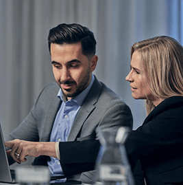 Two colleagues sitting by the computer talking