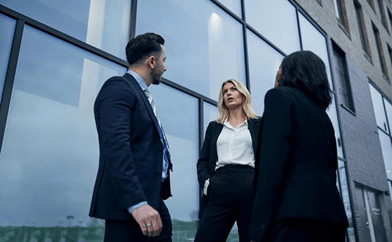 Tre personer i kostym, utanför en byggnad