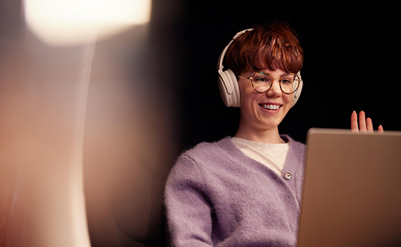 A woman waving to someone in a call on her computer
