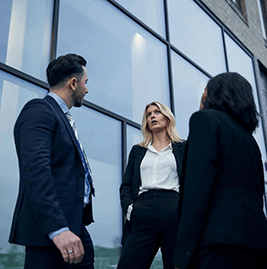 Three people standing outside of a building, talking