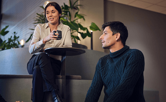Two colleagues drinking coffee, listening to another colleague