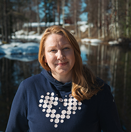 A woman with red hair looking into the camera, smiling