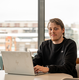A man sitting by his computer smiling to the camera