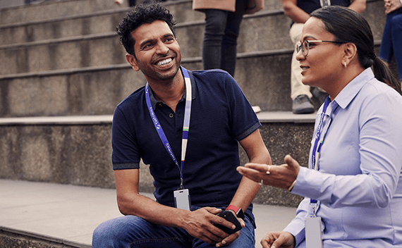Two colleagues sitting on a stair, talking and laughing