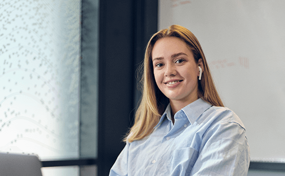 A woman sitting by her computer, smiling to the camera