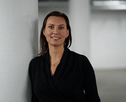 A woman with brown hair, smiling to the camera