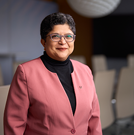 A woman with dark hair looking into the camera, smiling