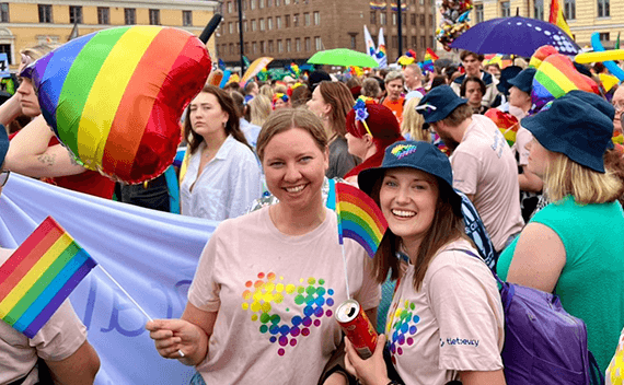 Två kvinnor som ler mot kameran under Pride-paraden i Helsingfors