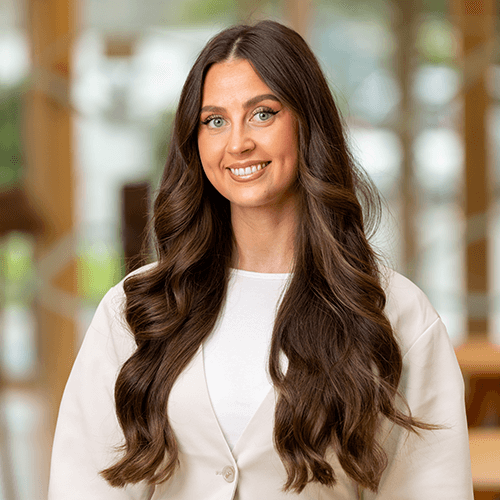 A woman with brown hair looking into the camera and smiling
