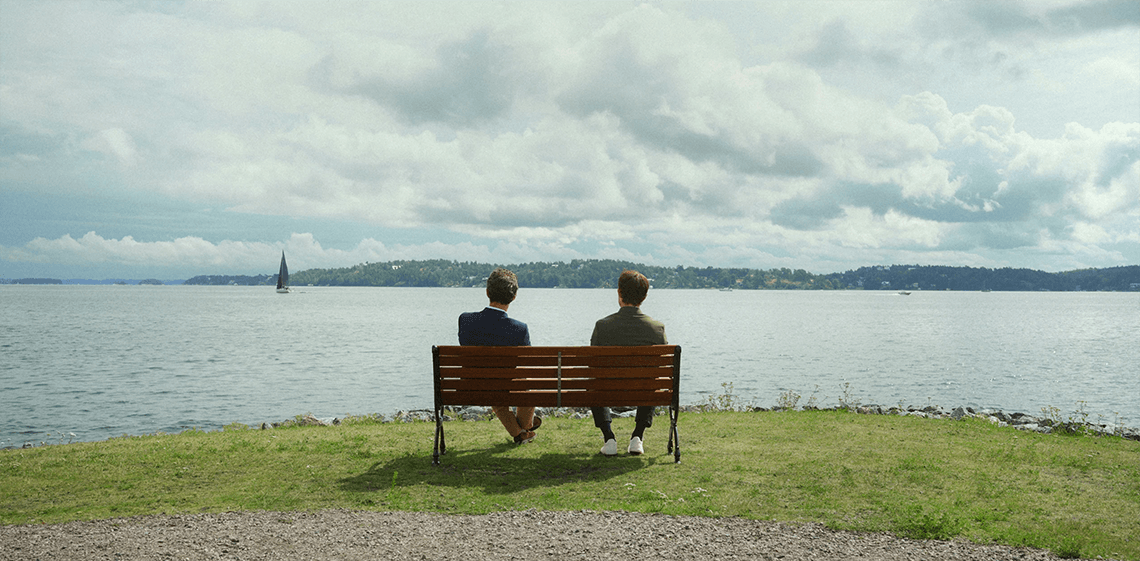 Two guys sitting on a bench with a nice view