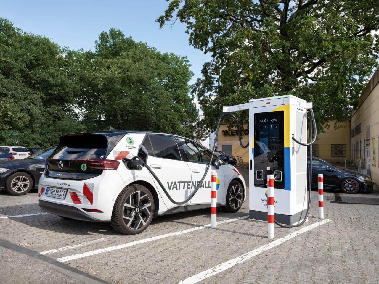 An electric car charging at a charging station in a parking lot on a sunny day.
