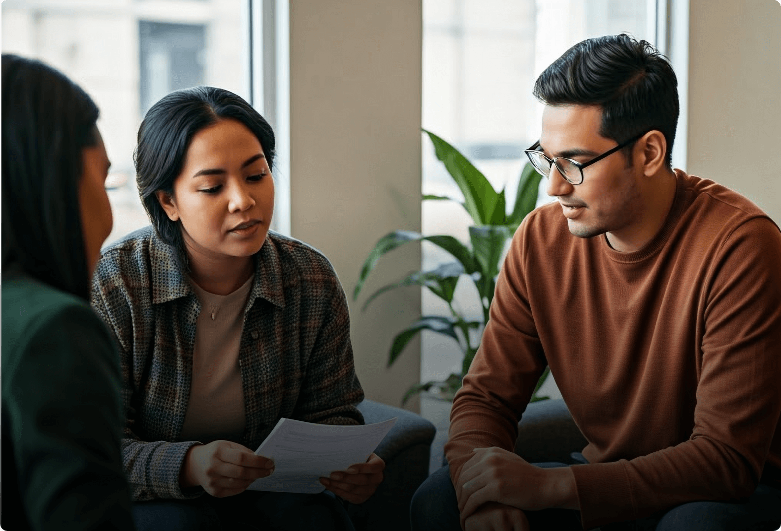 An image of three people sitting and looking over a document