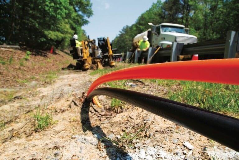 Workers installing cables by the roadside.