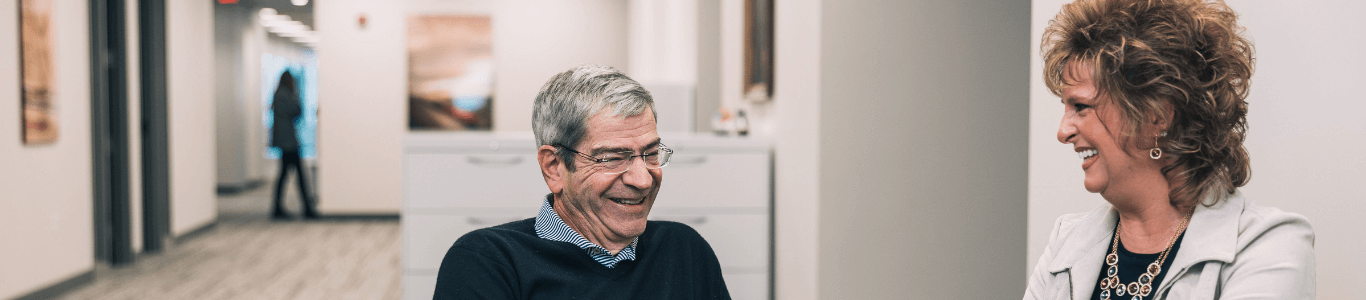 Two co-workers talking on a couch in the office and smiling