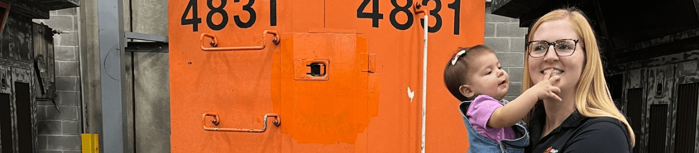 Woman holding child in front of train car