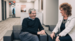 Two co-workers talking on a couch in the office and smiling